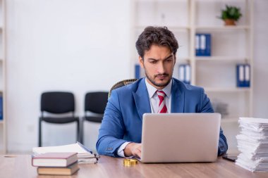 Genç bir erkek çalışan ve ofiste çok fazla iş var.