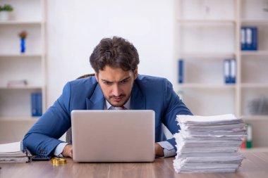 Genç bir erkek çalışan ve ofiste çok fazla iş var.