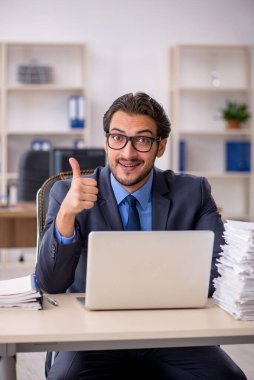 Genç bir erkek çalışan ve ofiste çok fazla iş var.