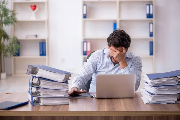 Jonge mannelijke werknemer ongelukkig met overmatig werk in het kantoor — Stockfoto