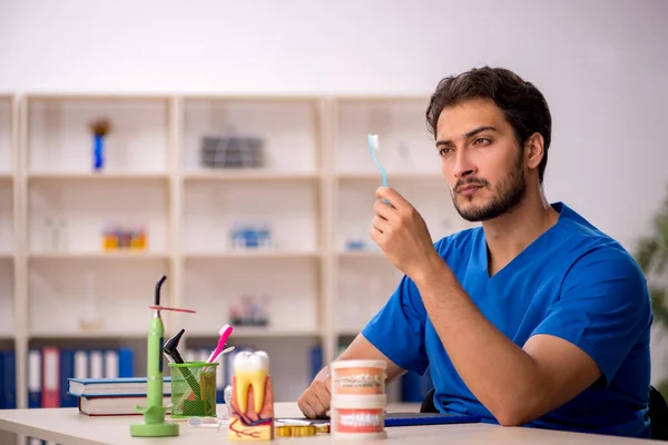 Jonge mannelijke tandarts werkzaam in de kliniek — Stockfoto