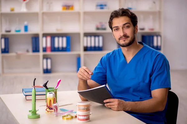 Jonge mannelijke tandarts werkzaam in de kliniek — Stockfoto