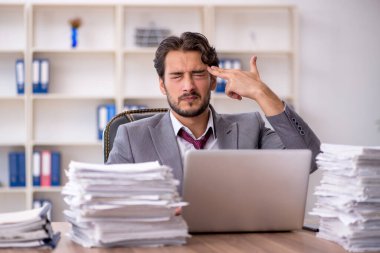 Genç bir erkek çalışan ve ofiste çok fazla iş var.