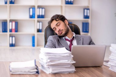 Genç bir erkek çalışan ve ofiste çok fazla iş var.