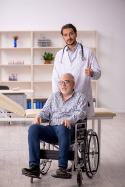 Tekerlekli sandalyedeki yaşlı adam genç erkek doktoru ziyaret ediyor.