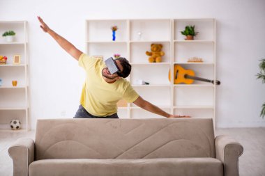 Evde sanal gözlük takan genç bir adam.