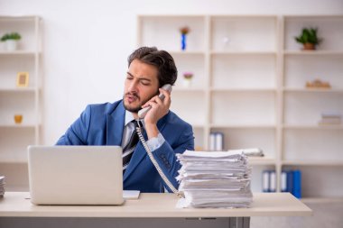 Genç bir erkek çalışan ve ofiste çok fazla iş var.