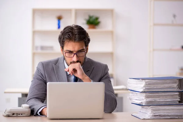 Ung manlig anställd och för mycket arbete på kontoret — Stockfoto