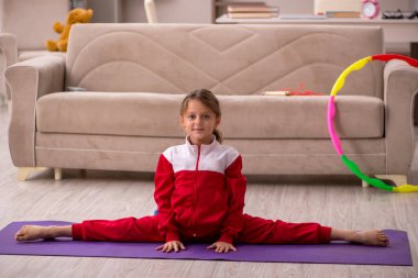 Küçük kız evde spor yapıyor.