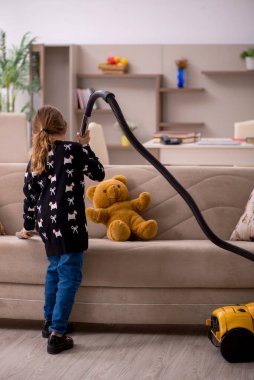 Küçük kız evde ev işi yapıyor.