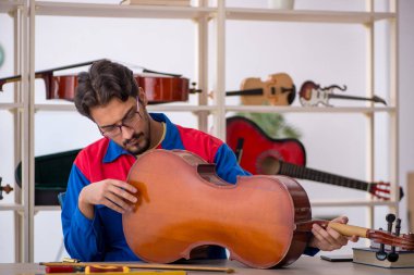 Genç adam atölyede müzik aletlerini tamir ediyor.