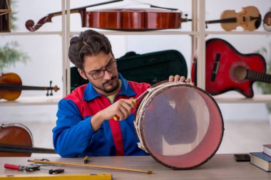Genç adam atölyede müzik aletlerini tamir ediyor.
