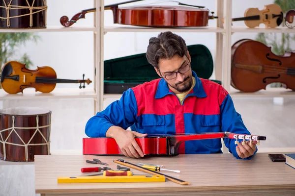 Joven reparando instrumentos musicales en el taller —  Fotos de Stock