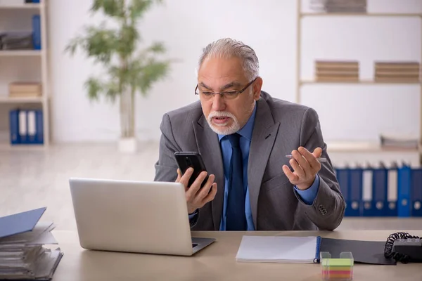 Old male employee working at workplace — Stock Photo, Image