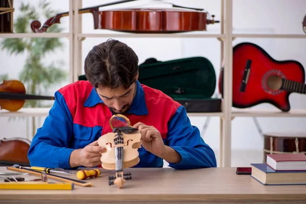 Genç adam atölyede müzik aletlerini tamir ediyor. — Stok fotoğraf