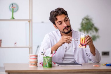 Klinikte çalışan genç erkek dişçi.