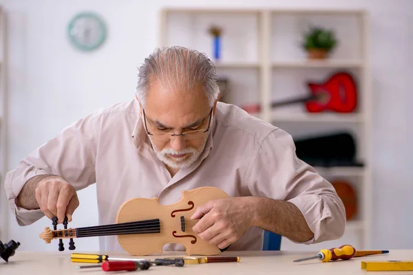 Vieux réparateur masculin réparant des instruments de musique à l'atelier — Photo