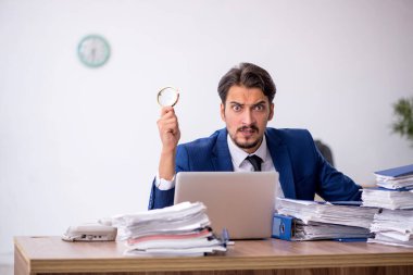 Genç bir erkek çalışan ve ofiste çok fazla iş var.