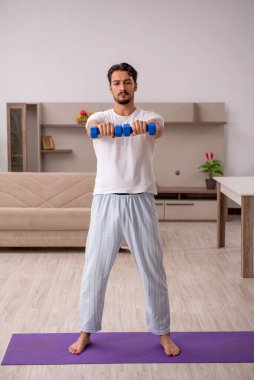 Genç adam evde spor yapıyor.