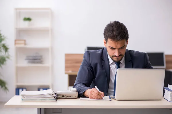 Junge männliche Mitarbeiter sitzen am Arbeitsplatz — Stockfoto