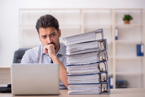 Joven empleado masculino y demasiado trabajo en la oficina — Foto de Stock