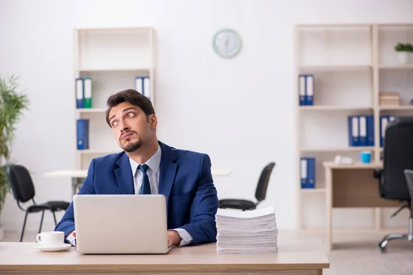 Ung mandlig medarbejder og for meget arbejde på kontoret - Stock-foto