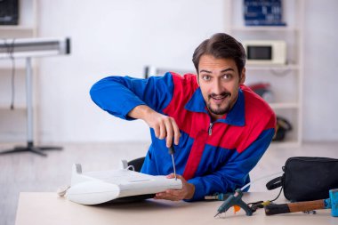 Genç erkek tamirci ısıtıcıyı tamir ediyor.