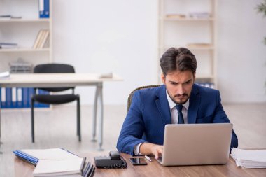 Ofisteki aşırı işten memnun olmayan genç bir erkek işçi.