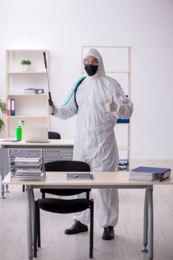 Young male contractor disinfecting office during pandemic