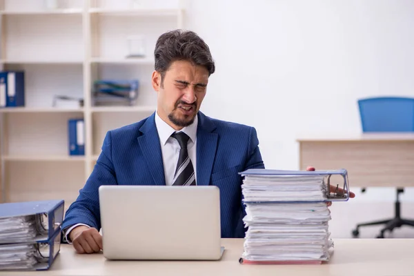 Joven empleado masculino y demasiado trabajo en la oficina — Foto de Stock