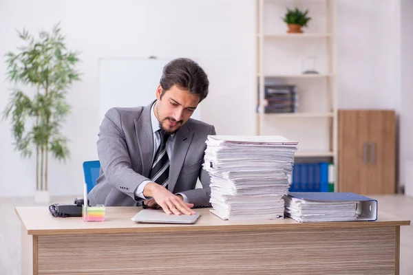 Ung manlig anställd och för mycket arbete på kontoret — Stockfoto