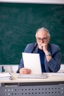 Sınıftaki yaşlı erkek öğretmen.