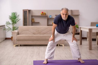 Yaşlı adam evde spor yapıyor.