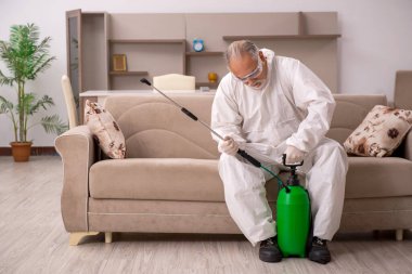 Yaşlı erkek müteahhit evde haşere kontrolü yapıyor.