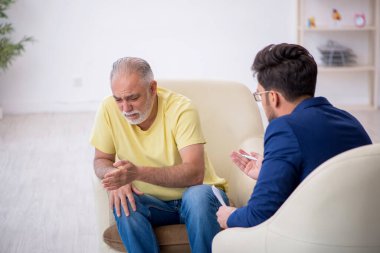 Yaşlı adam genç erkek psikoterapisti ziyaret ediyor.