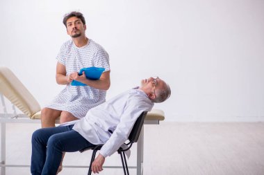 Yaşlı erkek doktor psikiyatrist genç erkek hastayı muayene ediyor.