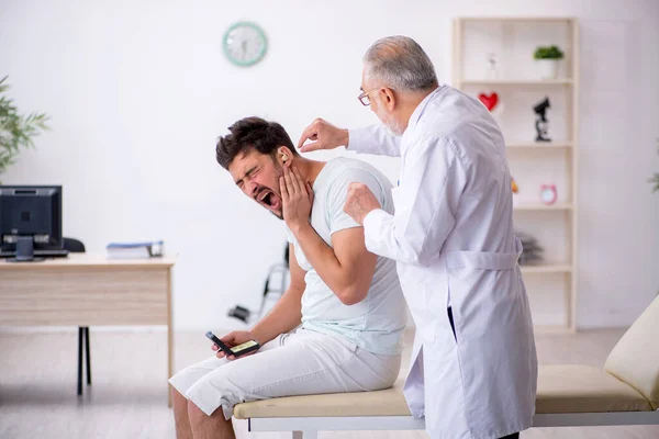 Ung manlig patient med hörselproblem besöker gammal läkare otor — Stockfoto