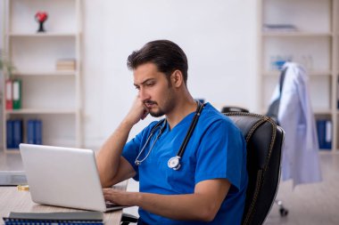 Klinikte çalışan genç erkek doktor.