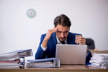 Genç bir erkek çalışan ve ofiste çok fazla iş var.