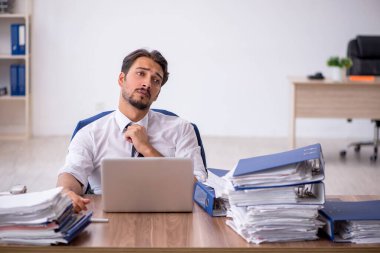 Genç bir erkek çalışan ve ofiste çok fazla iş var.