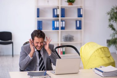 Genç erkek çalışan işyerinde yeni doğan çocuğa bakıyor.