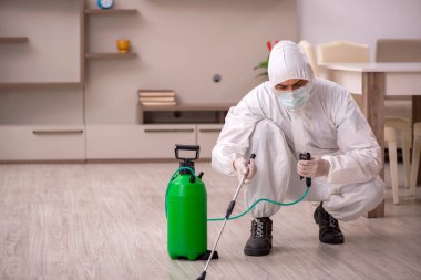 Genç erkek müteahhit evde haşere kontrolü yapıyor.