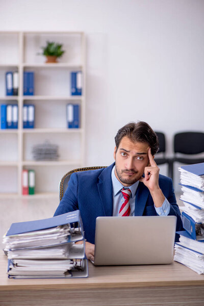 Young male employee and too much work in the office