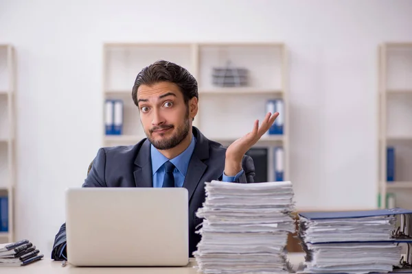 Jovem funcionário masculino e muito trabalho no escritório — Fotografia de Stock