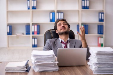 Genç bir erkek çalışan ve ofiste çok fazla iş var.