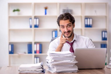 Genç bir erkek çalışan ve ofiste çok fazla iş var.