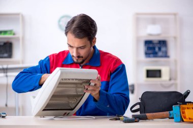 Genç erkek tamirci ısıtıcıyı tamir ediyor.