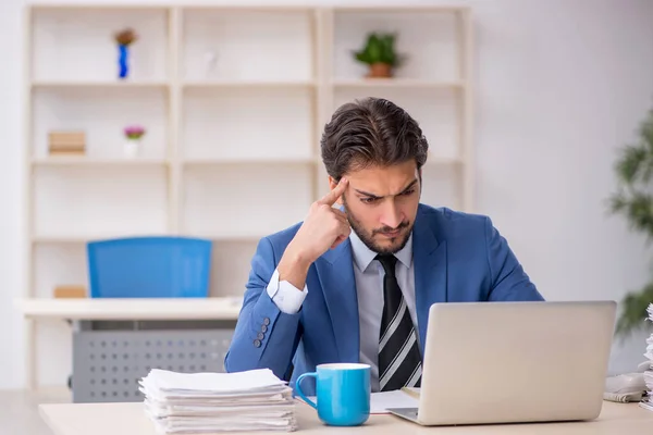 Joven empleado masculino y demasiado trabajo en la oficina — Foto de Stock