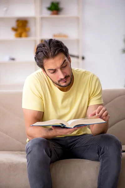 Genç adam salgın sırasında evde kitap okuyor. — Stok fotoğraf