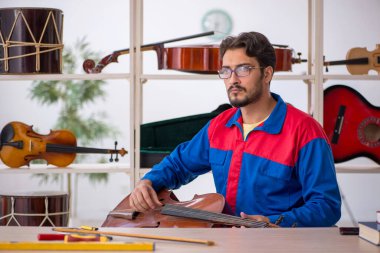 Genç adam atölyede müzik aletlerini tamir ediyor.